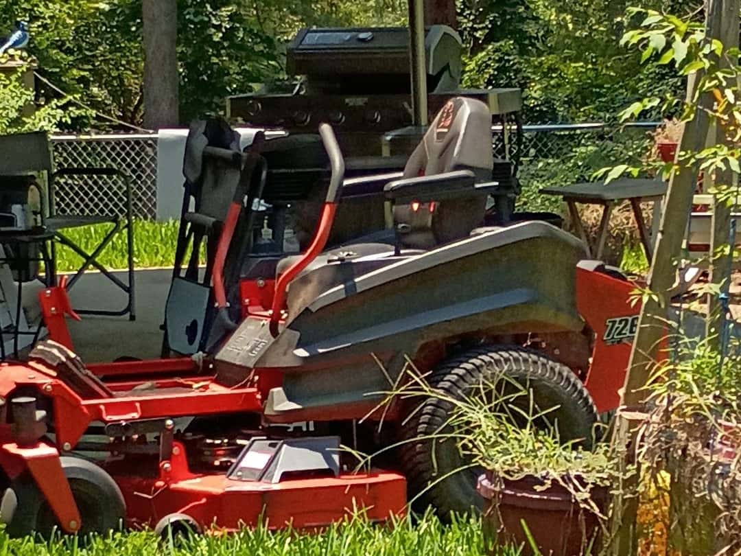 A red zero-turn mower parked on thick green grass